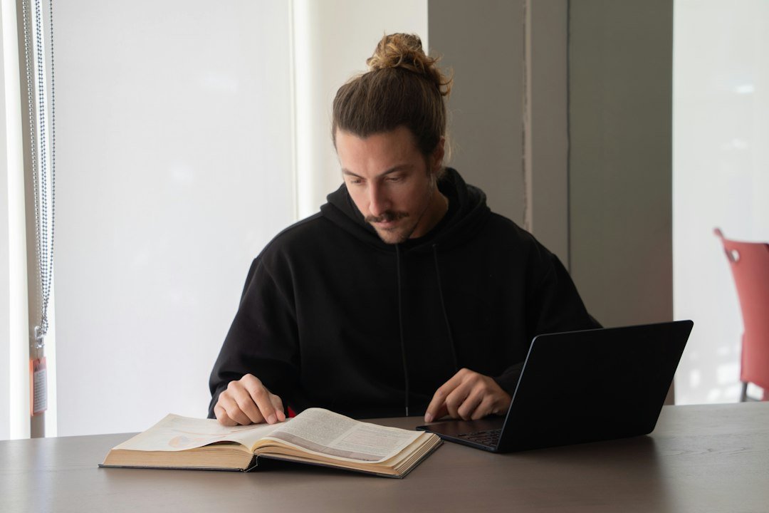 Student reading and using a laptop to build computer skills